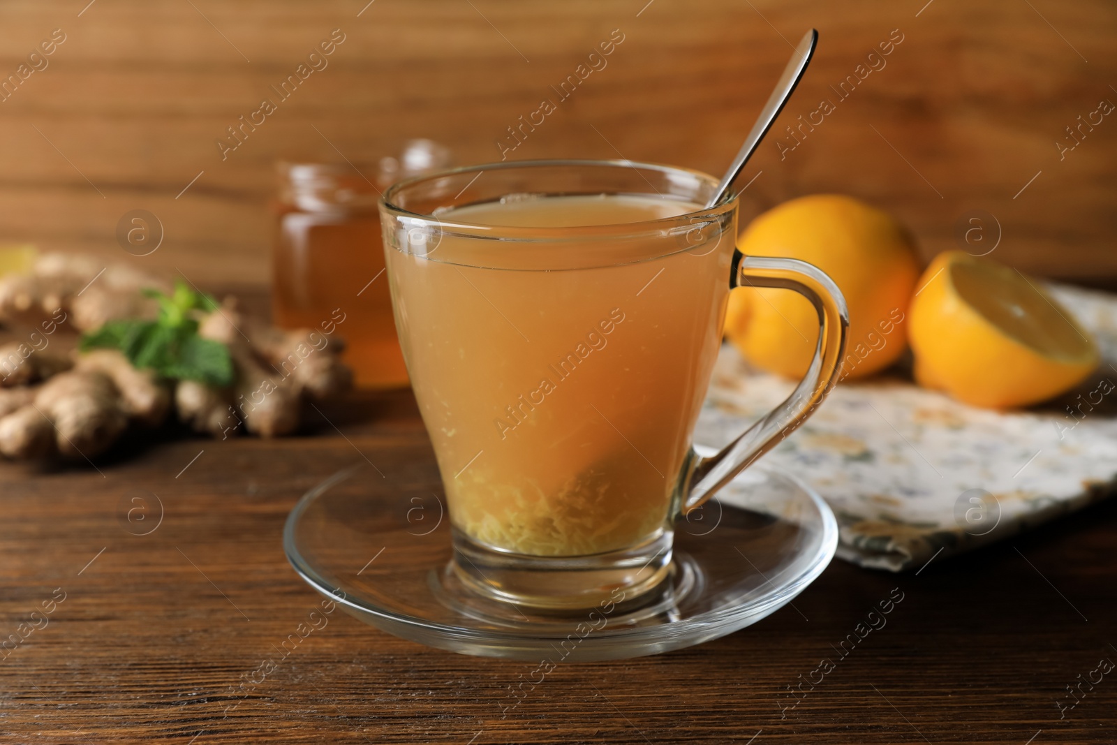 Photo of Cup of delicious ginger tea and ingredients on wooden table
