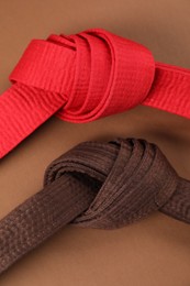 Photo of Colorful karate belts on brown background, flat lay