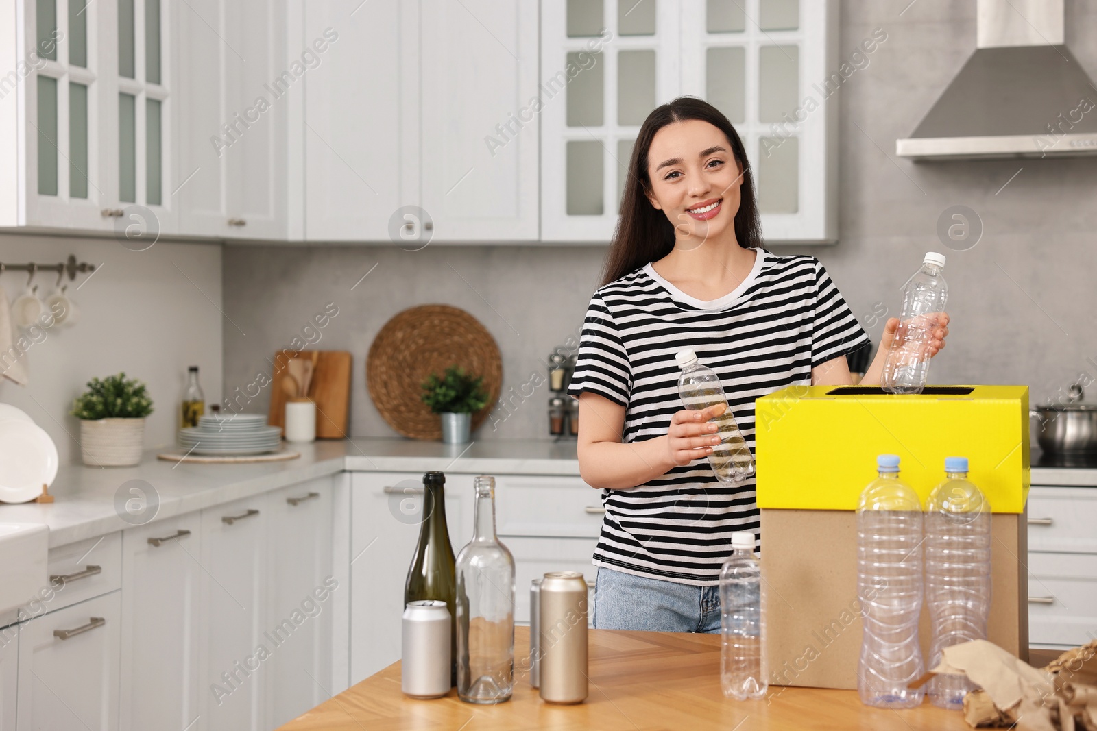 Photo of Smiling woman separating garbage in kitchen. Space for text