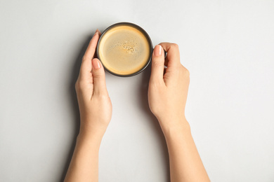 Photo of Woman with cup of coffee on light background, top view