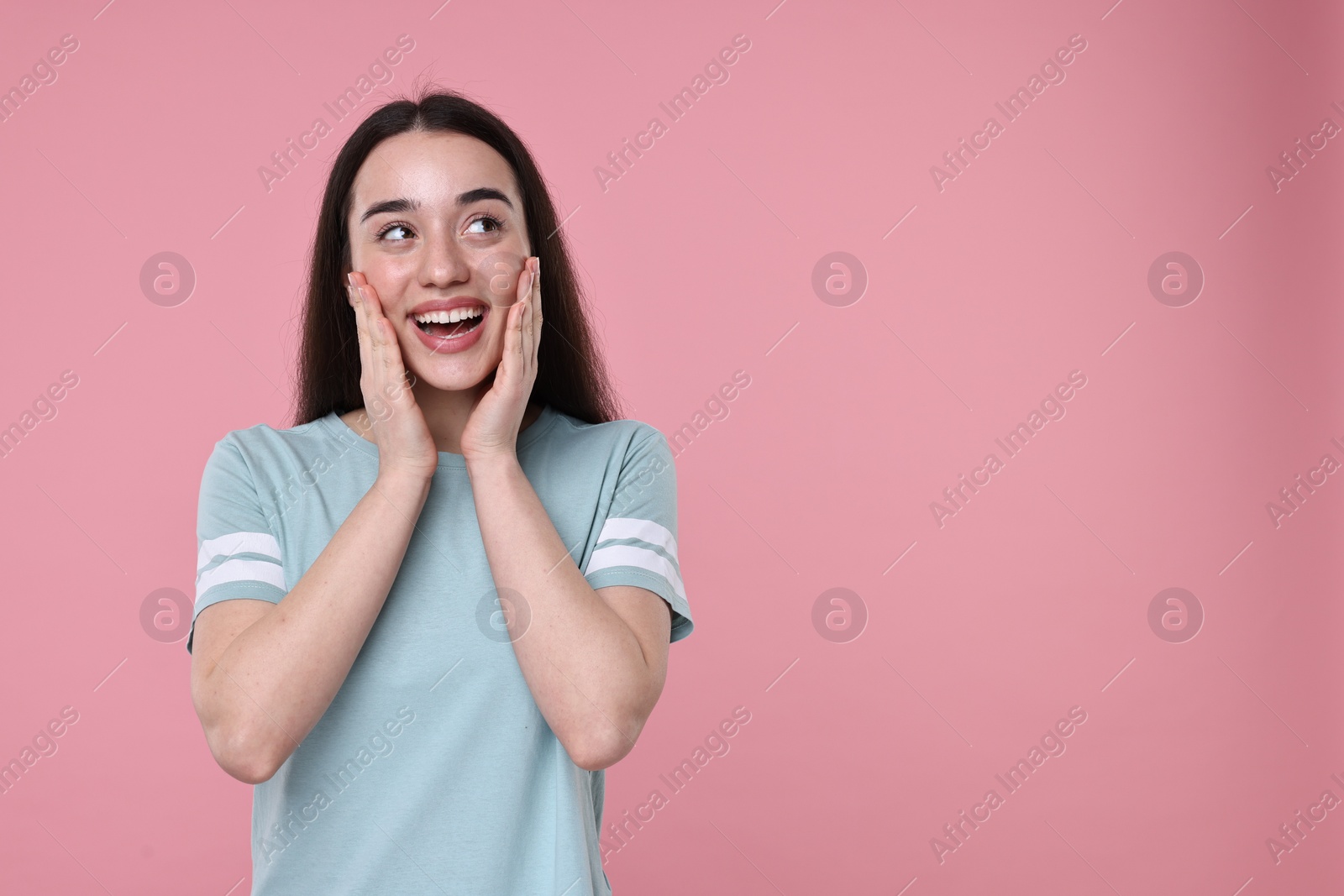 Photo of Portrait of happy surprised woman on pink background. Space for text