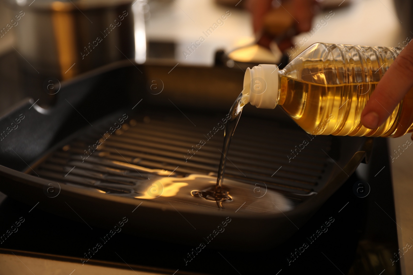 Photo of Man pouring cooking oil into frying pan in kitchen, closeup