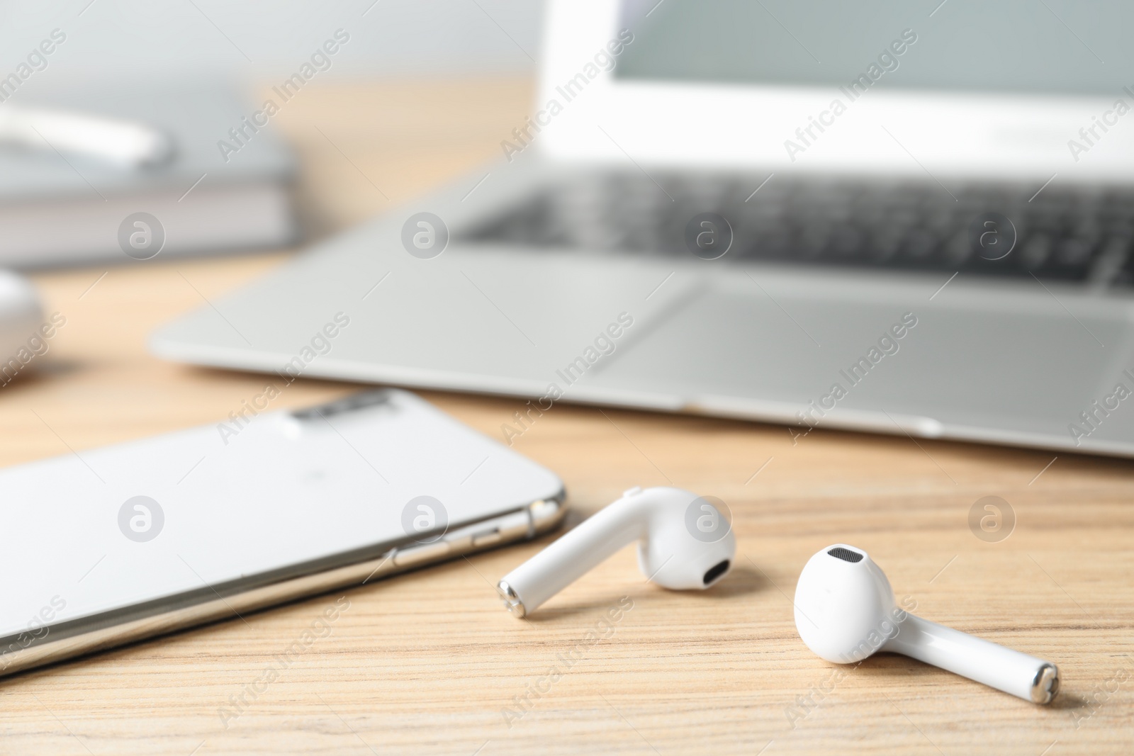 Photo of Earphones, smartphone and laptop on wooden table