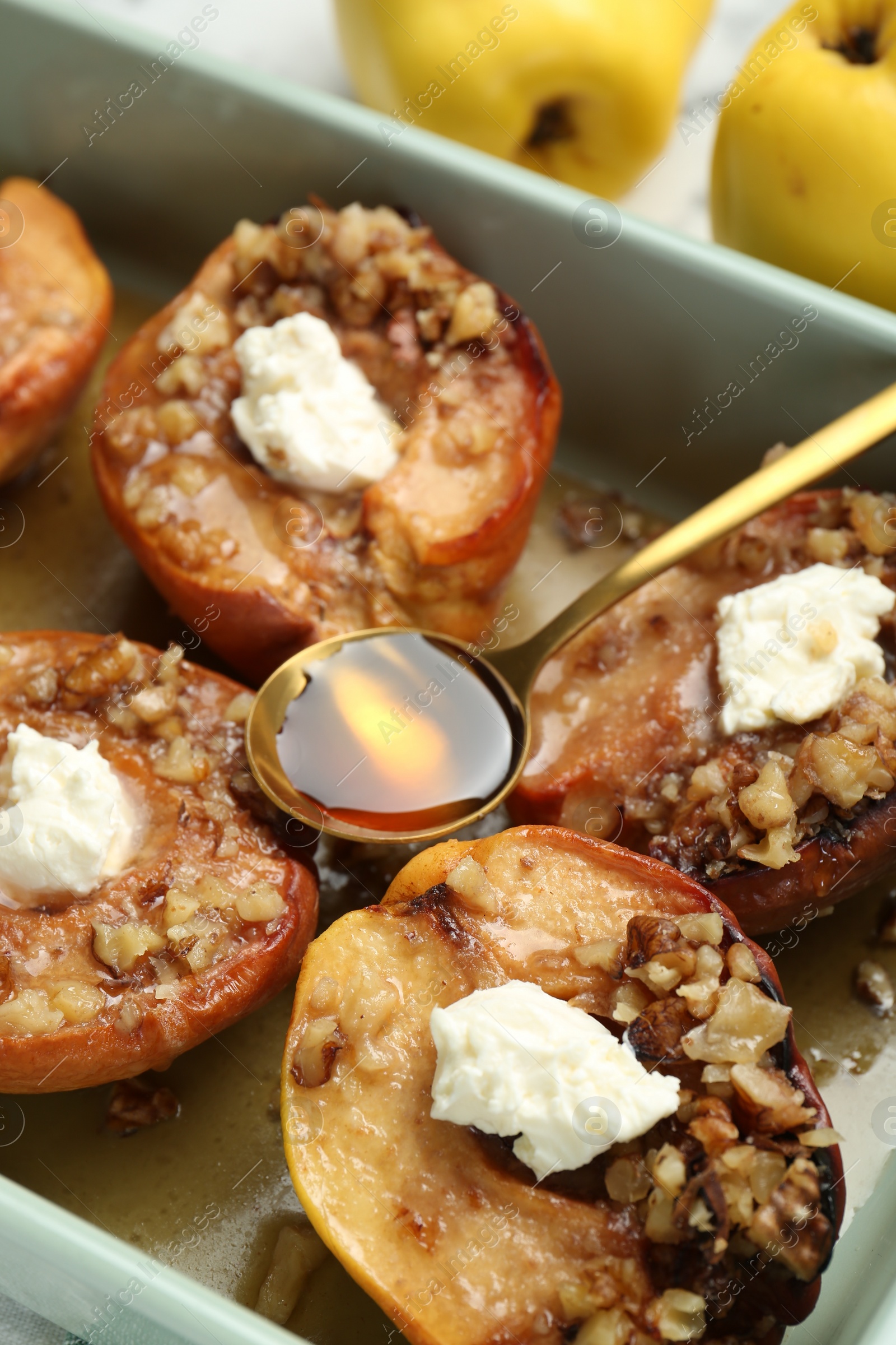 Photo of Tasty baked quinces with nuts, honey and cream cheese in dish, closeup