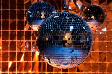 Photo of Shiny disco balls against foil party curtain under color lights