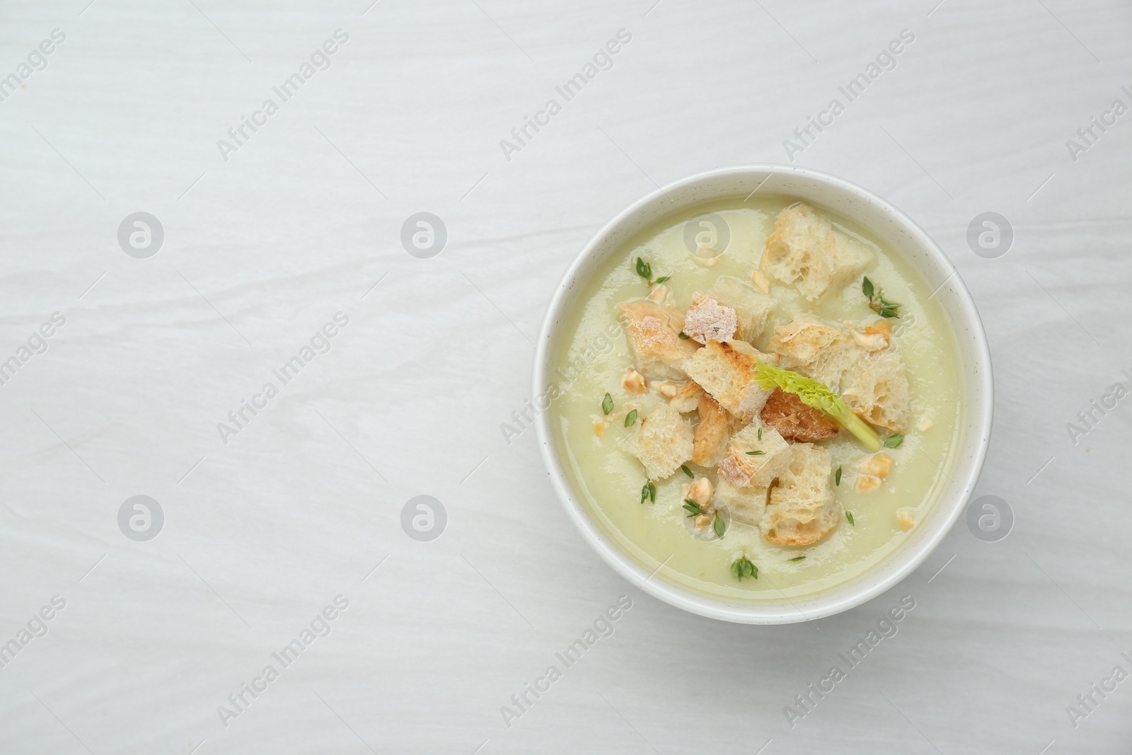 Photo of Delicious celery soup on white wooden table, top view. Space for text