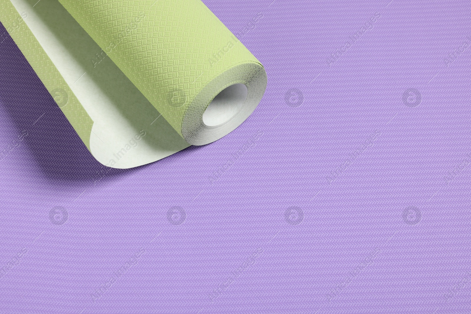 Photo of One green wallpaper roll on violet sample, space for text