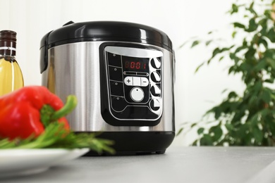 Photo of Modern multi cooker and products on kitchen table. Space for text