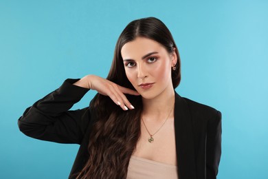 Beautiful woman with elegant jewelry on light blue background