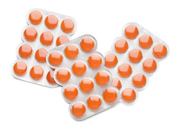 Blisters with orange cough drops on white background, top view