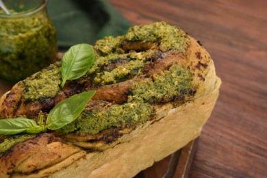 Photo of Freshly baked pesto bread with basil on wooden table, closeup