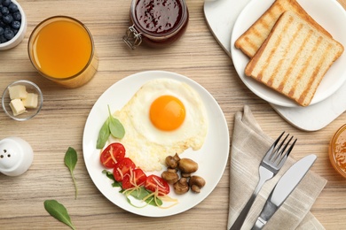 Photo of Tasty breakfast with fried egg served on wooden table, flat lay