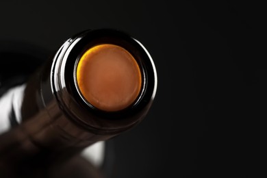 Photo of Wine bottle with cork on black background, closeup. Space for text