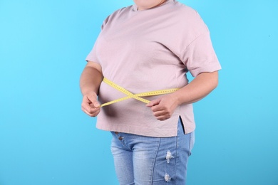 Photo of Fat woman with measuring tape on color background, closeup. Weight loss