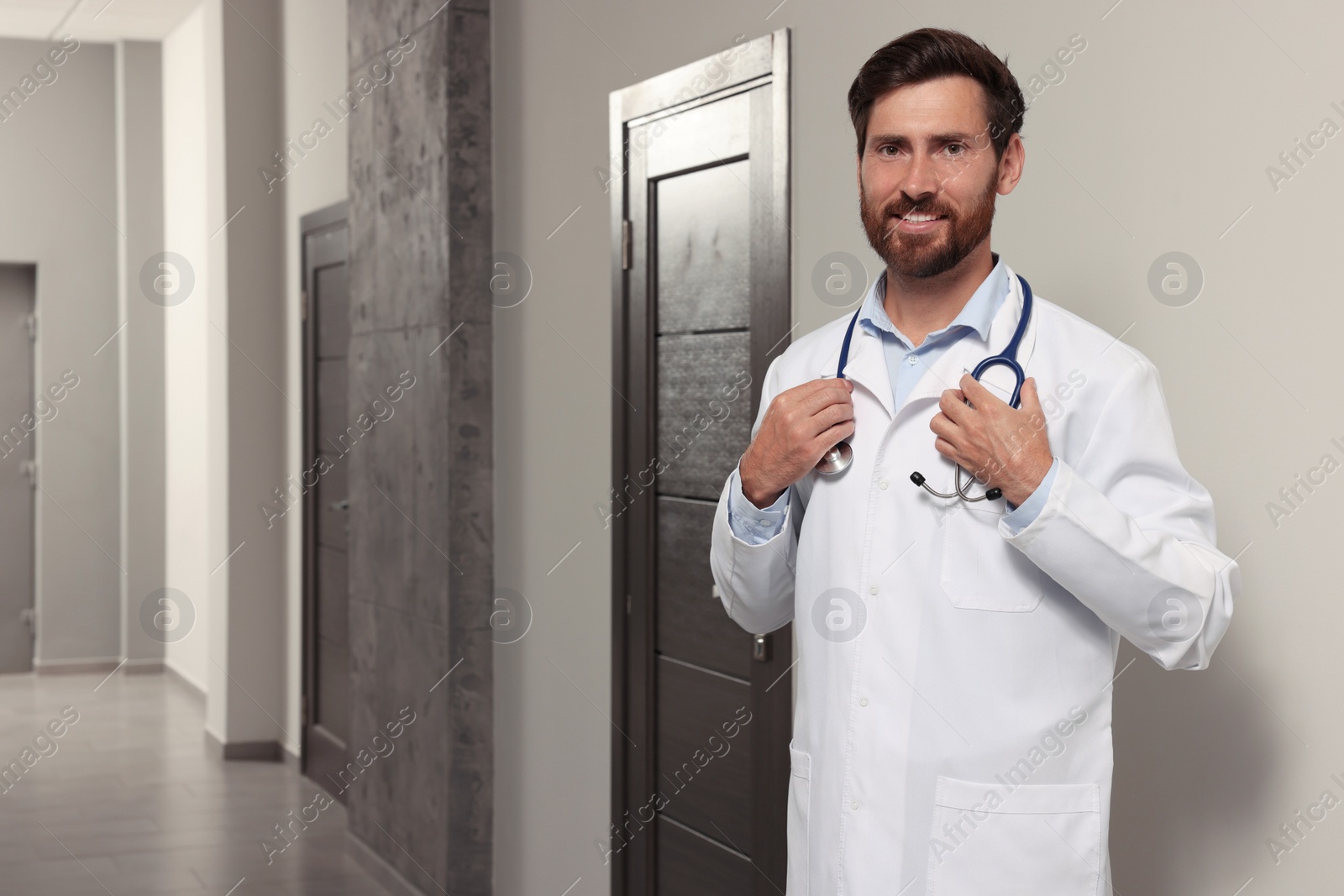 Photo of Doctor in white coat with stethoscope indoors. Space for text
