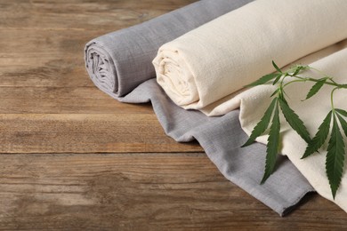 Photo of Hemp cloths and green branch on wooden table, space for text