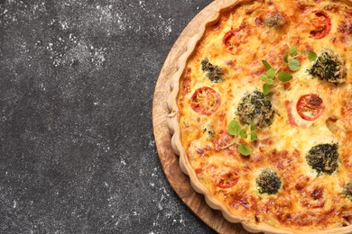 Delicious homemade vegetable quiche and oregano on black table, top view. Space for text