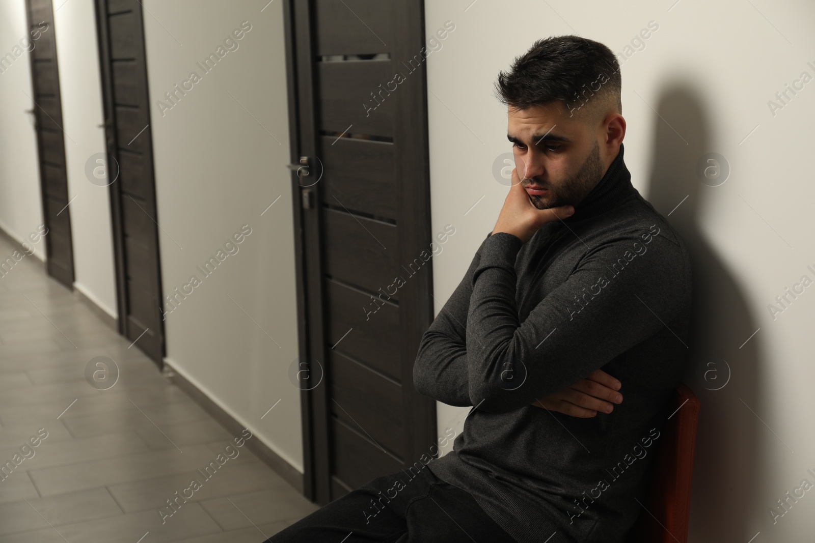 Photo of Sad young man in hall. Space for text