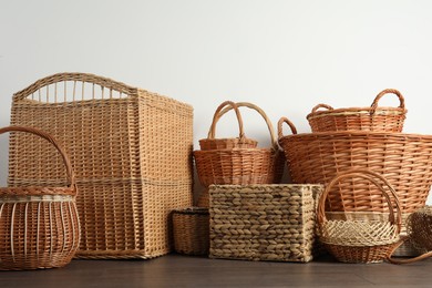 Photo of Many different wicker baskets made of natural material on floor near light wall