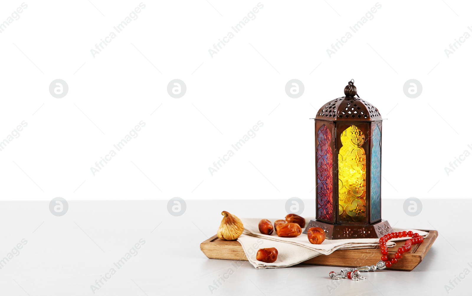 Photo of Muslim lamp, dates and prayer beads on table against white background. Space for text