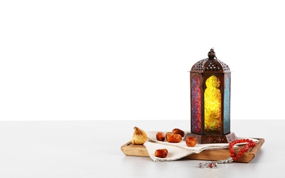 Muslim lamp, dates and prayer beads on table against white background. Space for text