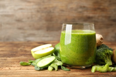 Photo of Green juice and fresh ingredients on wooden table. Space for text