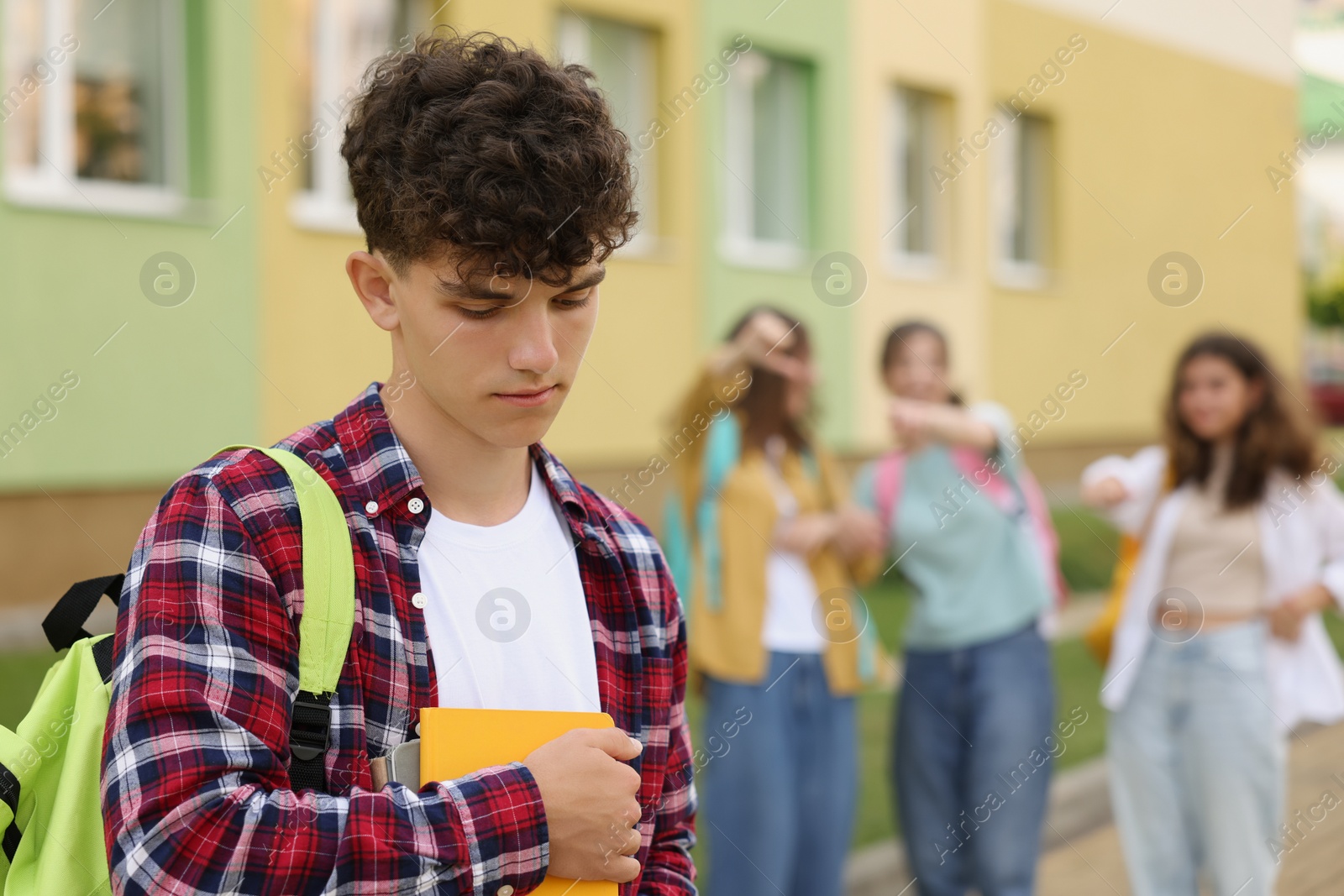 Photo of Teen problems. Group of students pointing at upset boy outdoors, selective focus