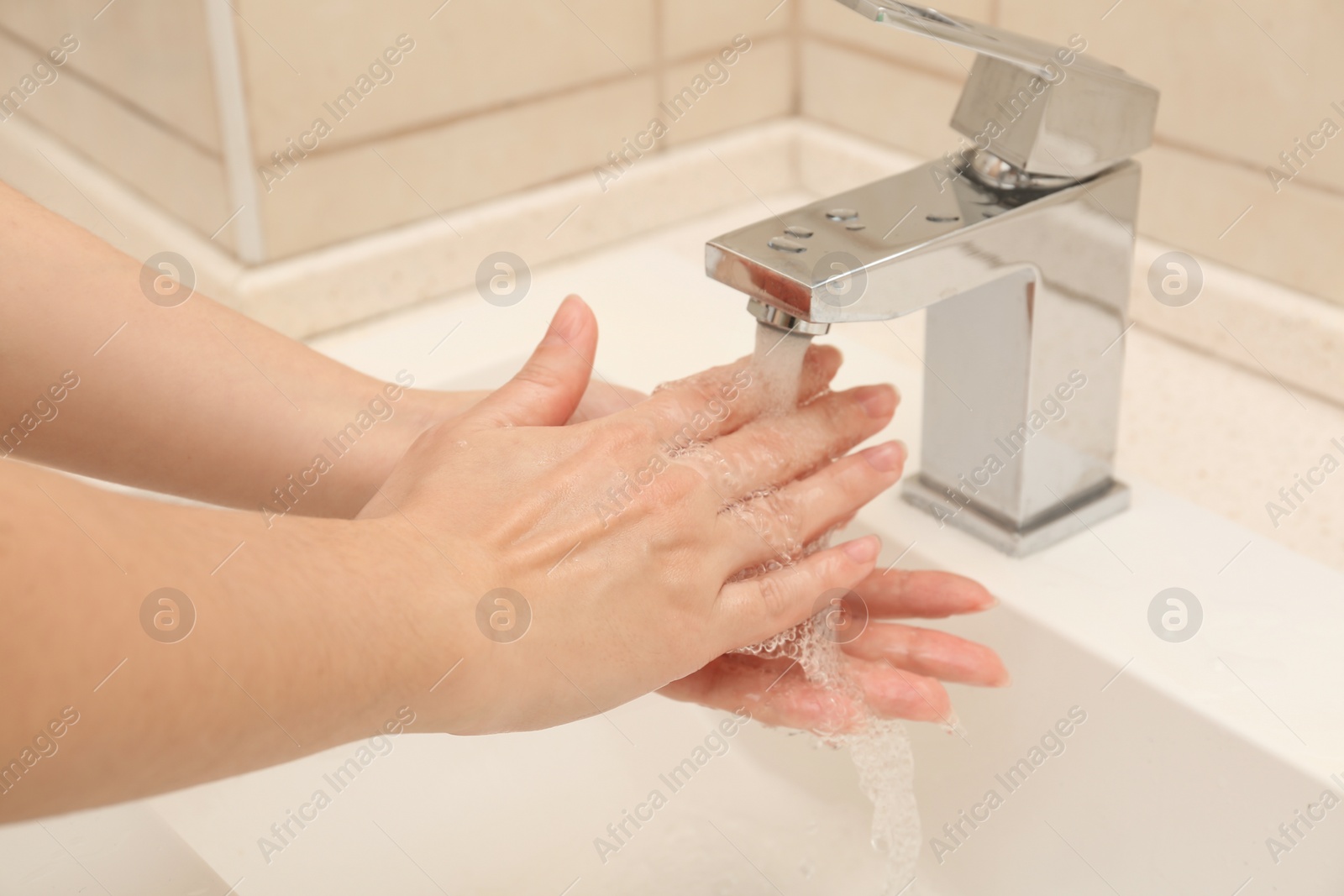 Photo of Woman washing hands with antiseptic soap in bathroom, closeup