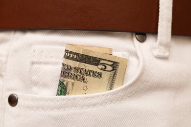 Photo of Dollar banknote in pocket of white jeans, closeup. Spending money