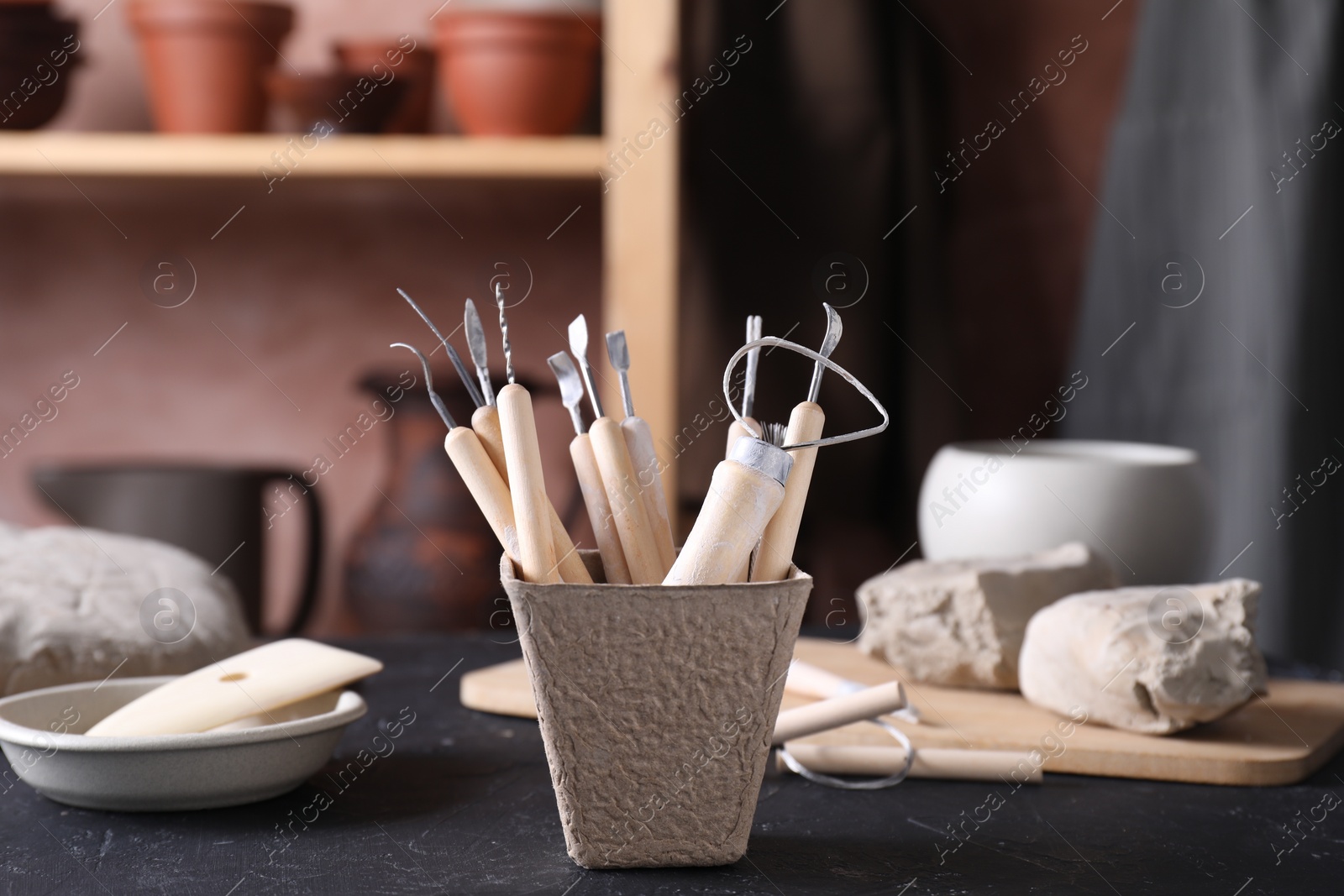 Photo of Clay and set of modeling tools on table in workshop