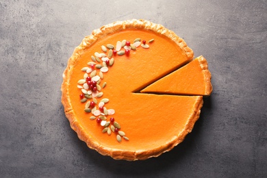 Photo of Fresh delicious homemade pumpkin pie on gray background, top view
