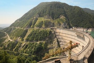 Photo of BATUMI, GEORGIA - AUGUST 13, 2022: Tower crane and hydroelectric power station in mountains