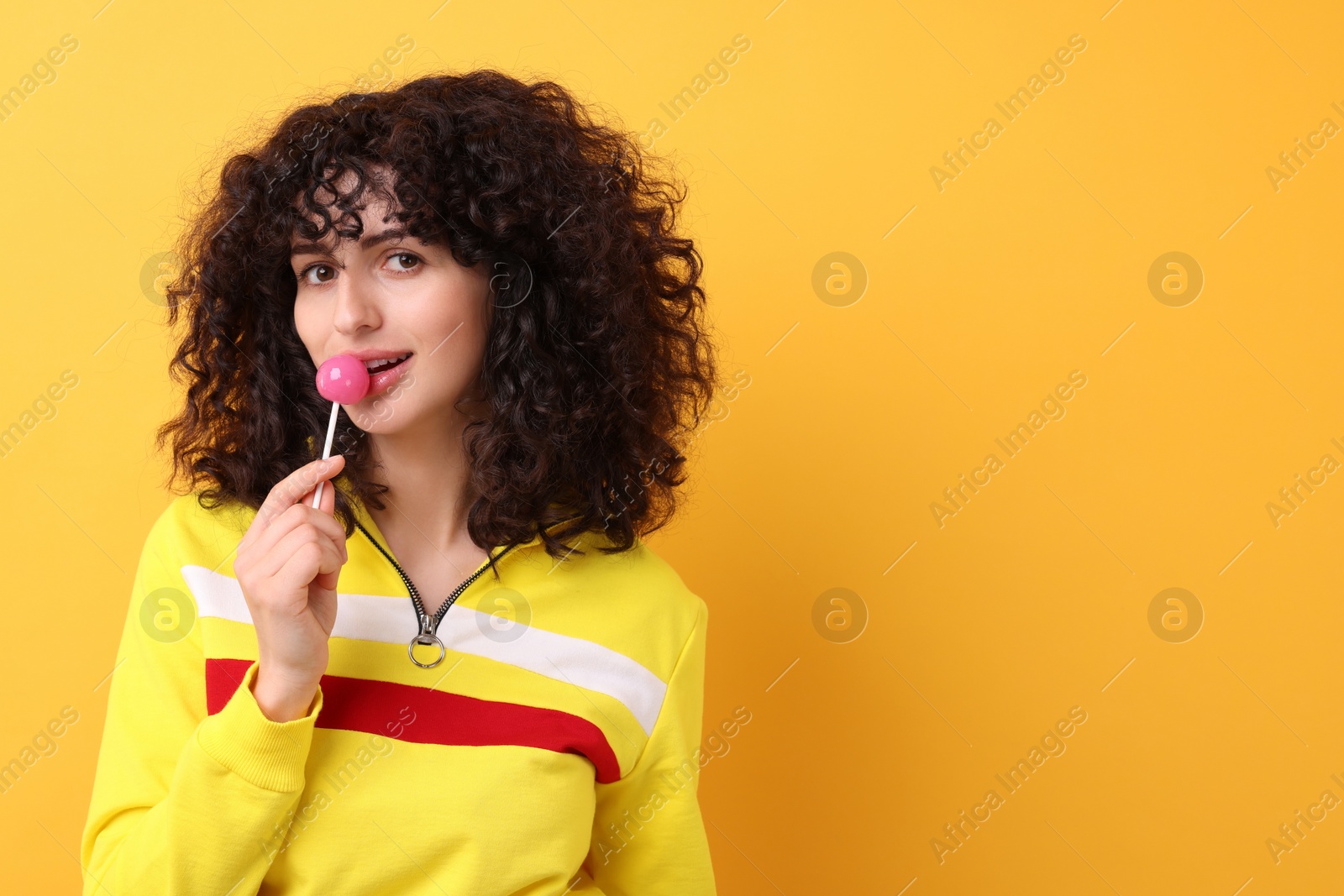 Photo of Beautiful woman with lollipop on yellow background, space for text