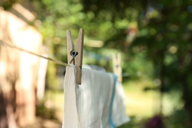 Photo of Washing line with clean laundry and clothespins outdoors, closeup. Space for text