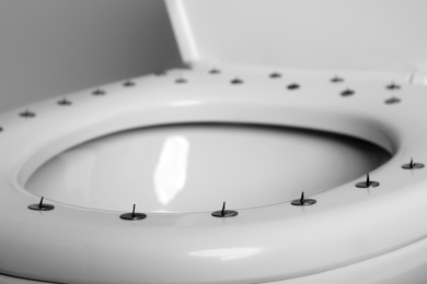 Photo of Toilet bowl with pins on white background, closeup. Hemorrhoids concept
