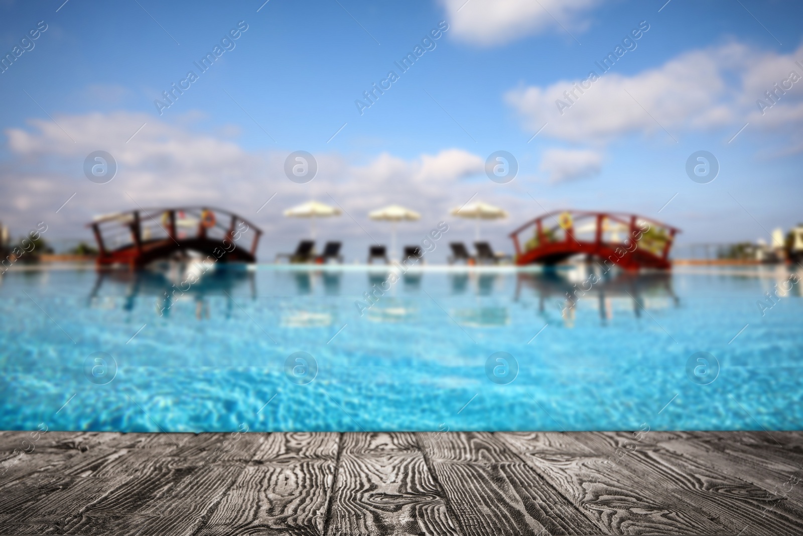 Image of Empty wooden surface near outdoor swimming pool with clear water. Space for design