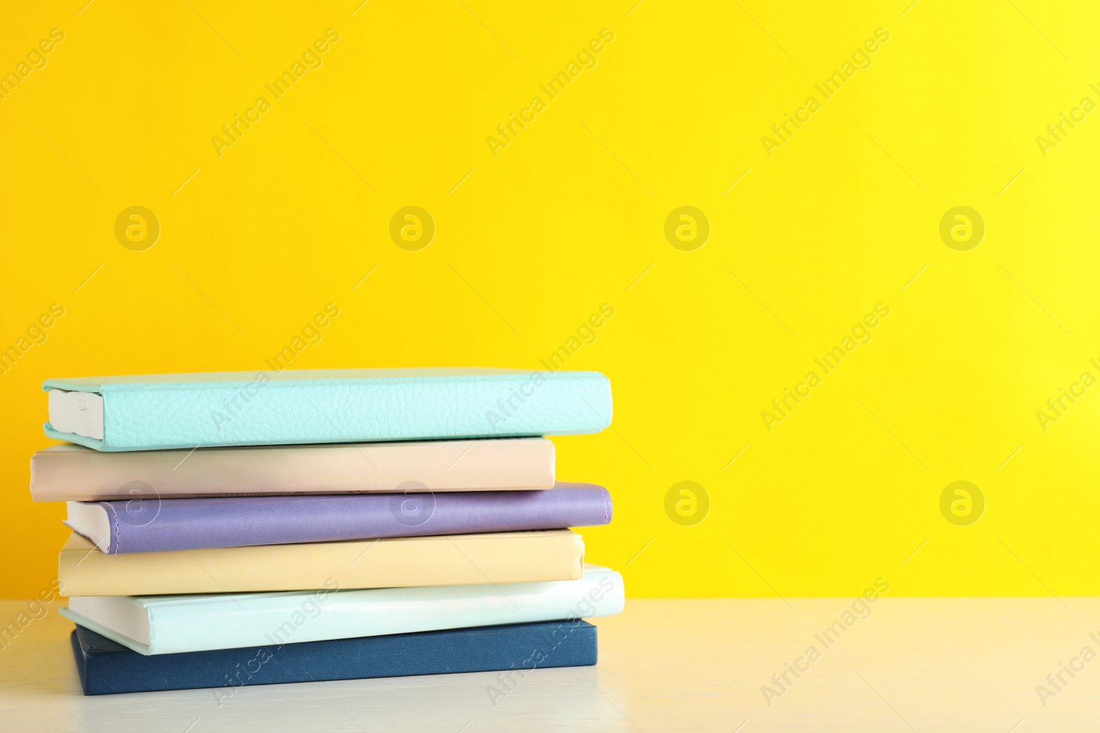 Photo of Stack of books on table against color background. Space for text