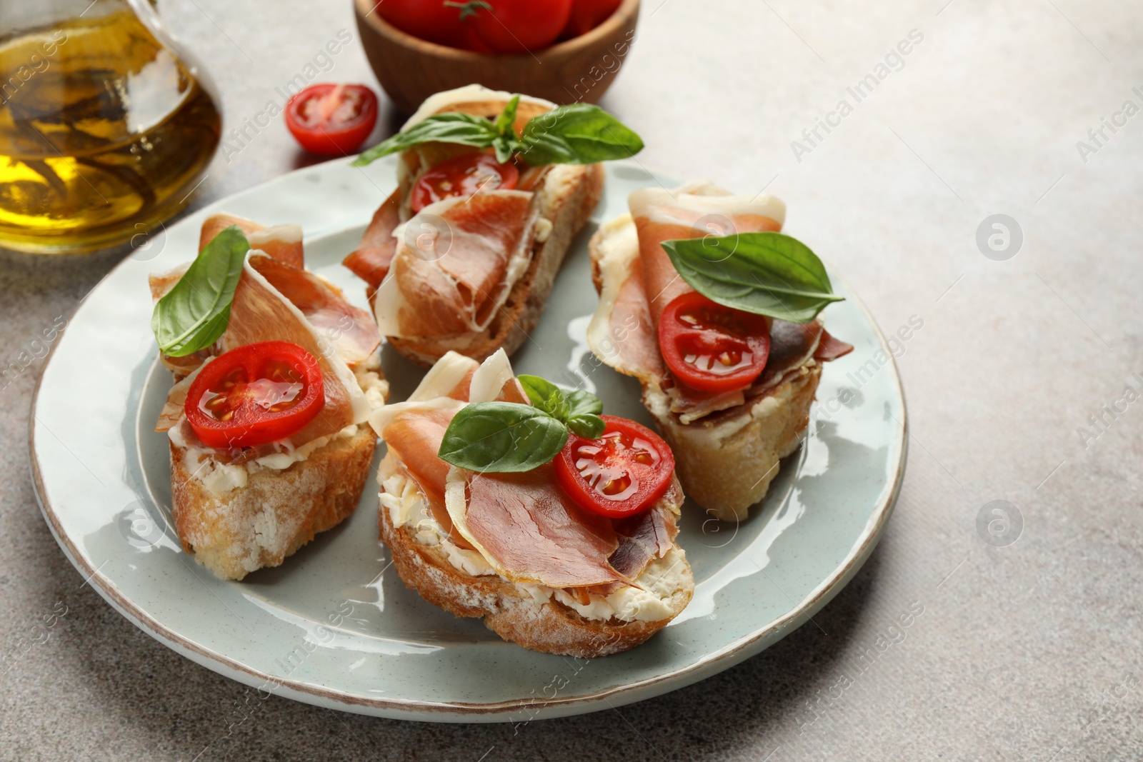 Photo of Tasty sandwiches with cured ham, basil and tomatoes on grey table