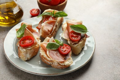 Tasty sandwiches with cured ham, basil and tomatoes on grey table