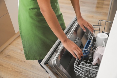 Photo of Woman opening dishwasher in kitchen, closeup. Cleaning chores