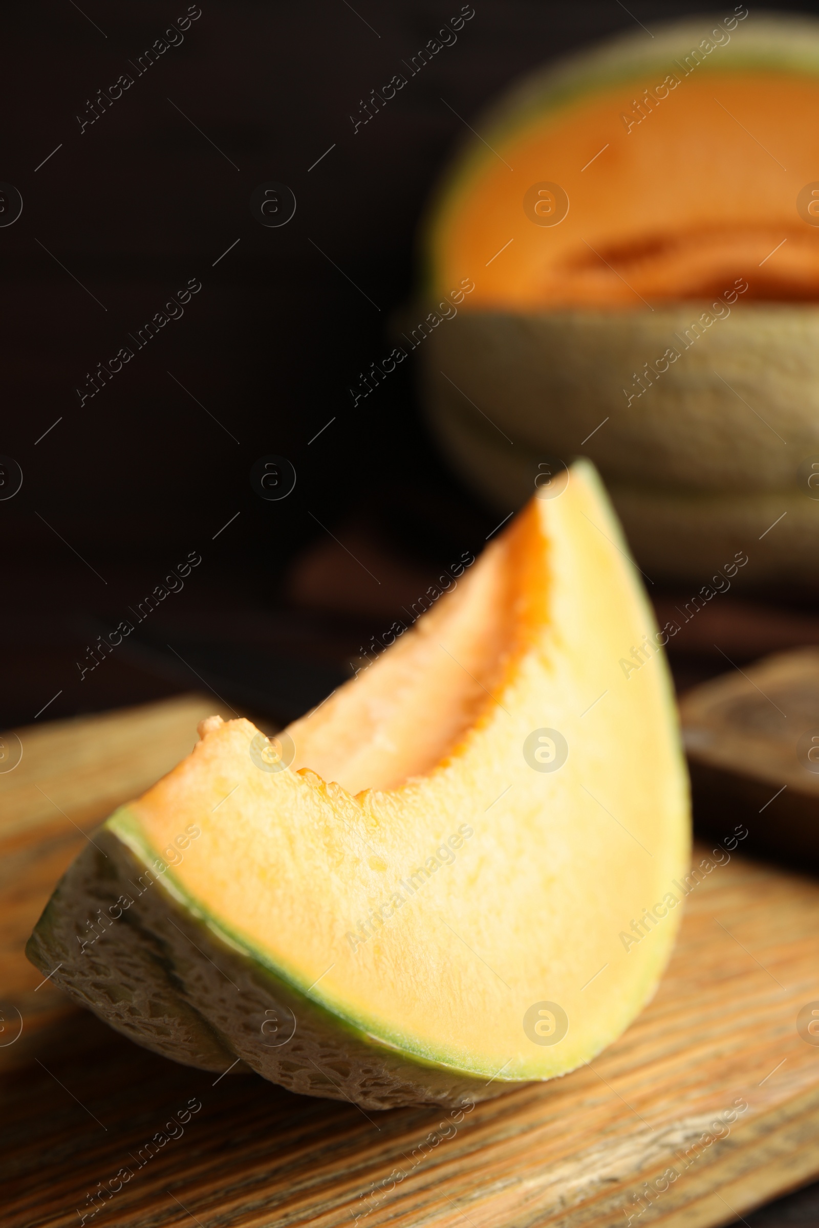 Photo of Slice of tasty fresh melon on wooden board, closeup