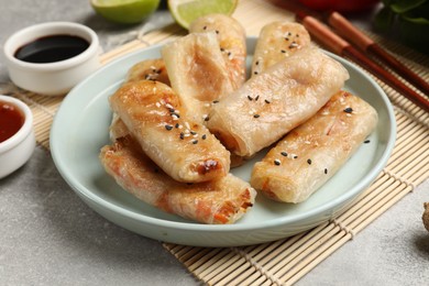 Photo of Tasty fried spring rolls served on gray table, closeup