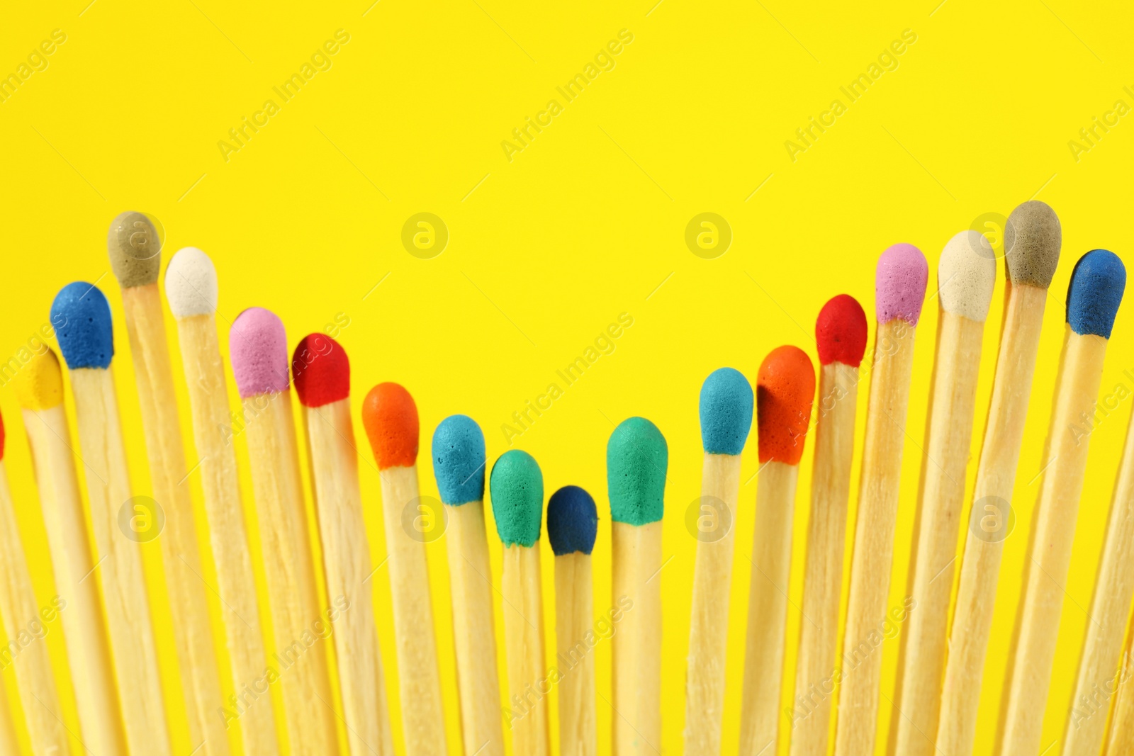 Photo of Matches with colorful heads on yellow background, closeup