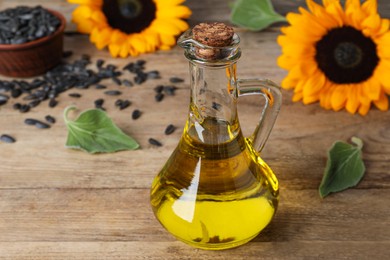 Photo of Sunflower cooking oil, seeds and yellow flowers on wooden table, closeup