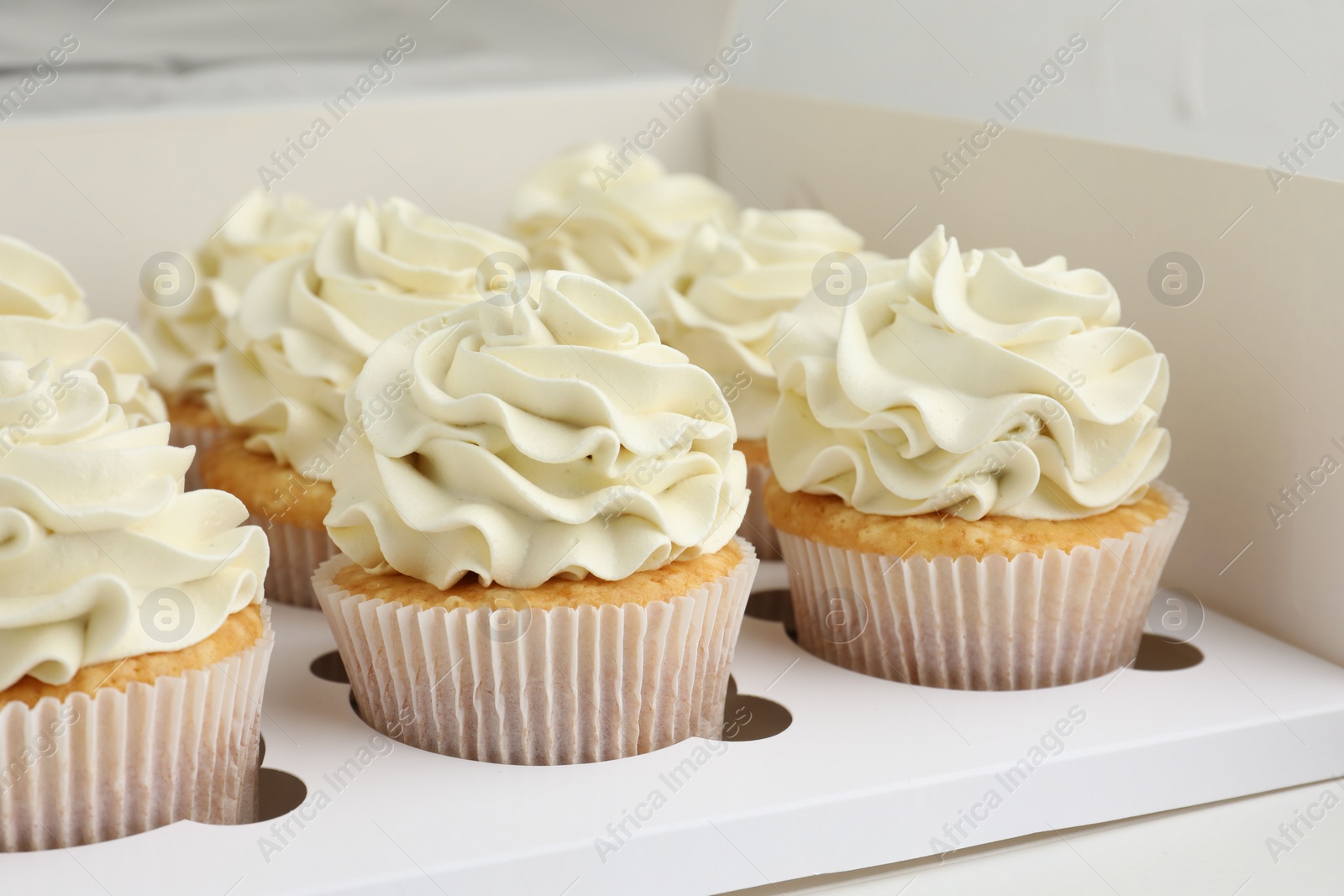 Photo of Tasty cupcakes with vanilla cream in box, closeup