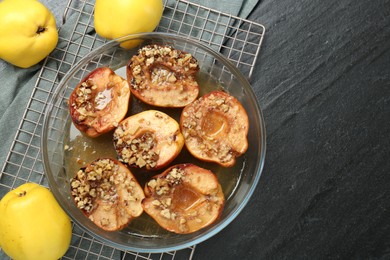 Photo of Tasty baked quinces with walnuts and honey in bowl on black table, flat lay. Space for text