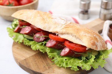 Photo of Delicious sandwich with sausages and vegetables on white table, closeup