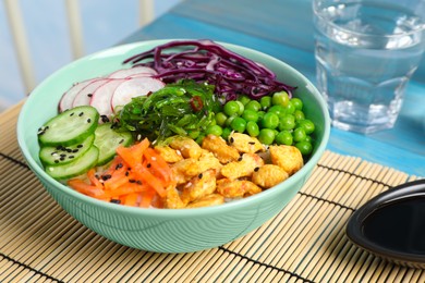 Photo of Delicious salad with chicken, vegetables and seaweed on light blue table, closeup