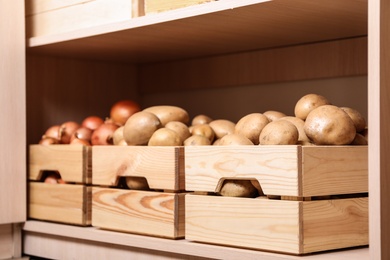 Photo of Crates with potatoes and onions on shelf. Orderly storage