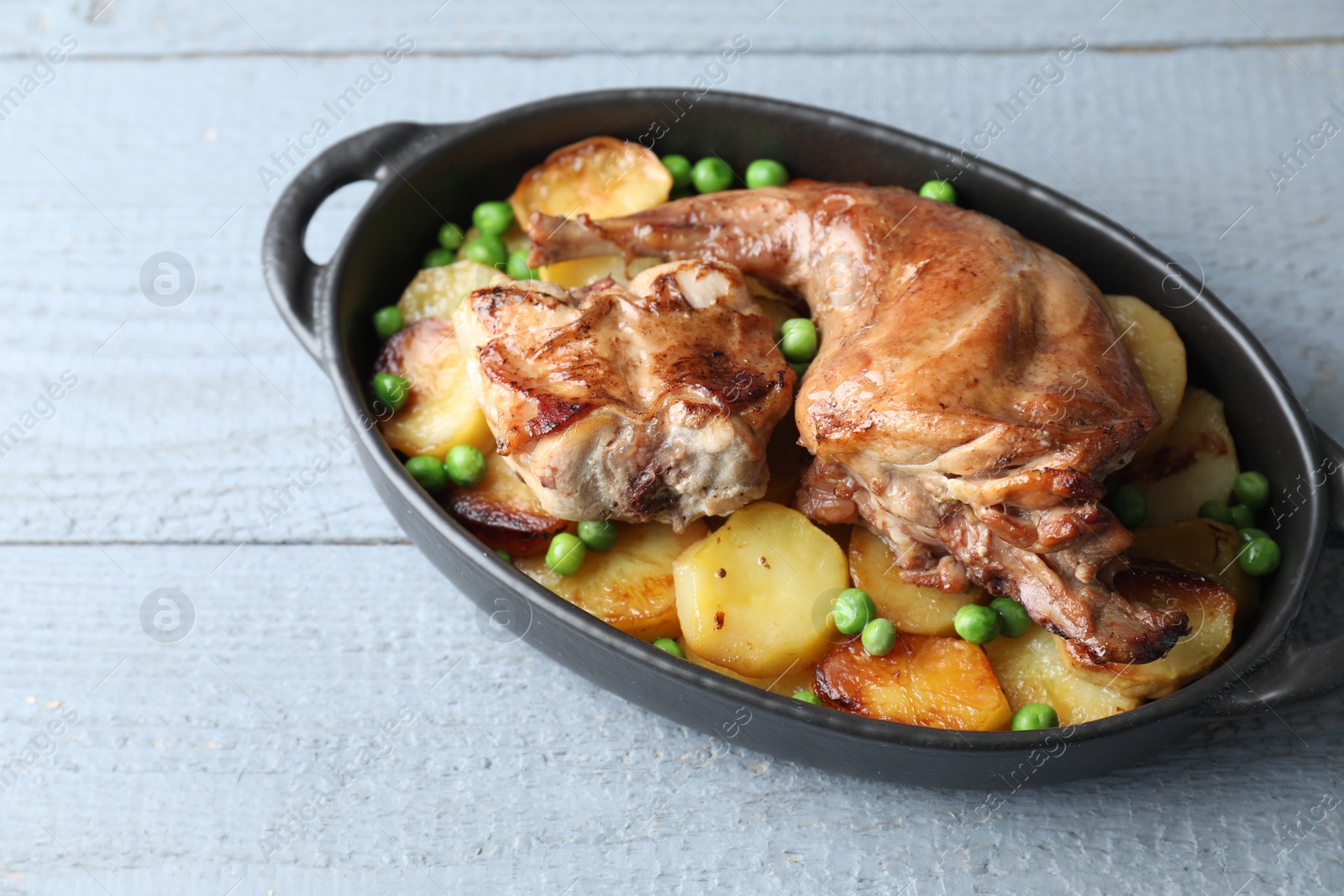 Photo of Tasty cooked rabbit with vegetables in baking dish on grey wooden table